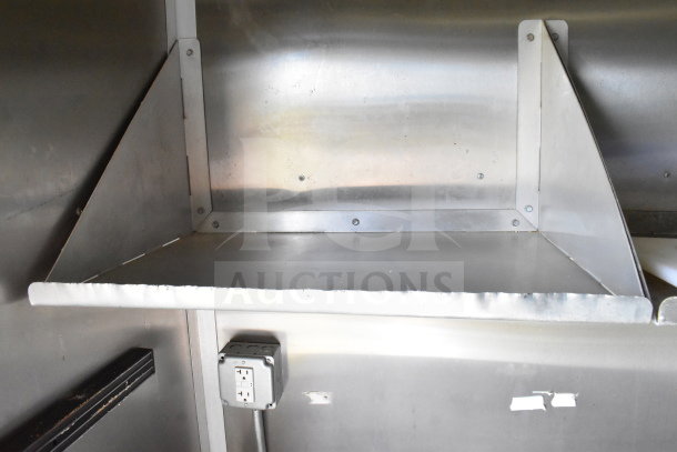 Interior view of 2020 Diamond Cargo 8.5'x24' food trailer, featuring a stainless steel shelf and electrical outlet.