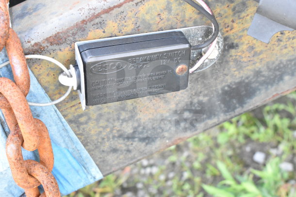 Close-up of ESCO breakaway switch on a 2020 Diamond Cargo food trailer. Rust visible on tow chains.