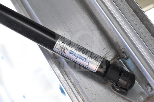 Strybuc Series gas spring, Part #SE200P-20, mounted on aluminum frame, features label with specifications.