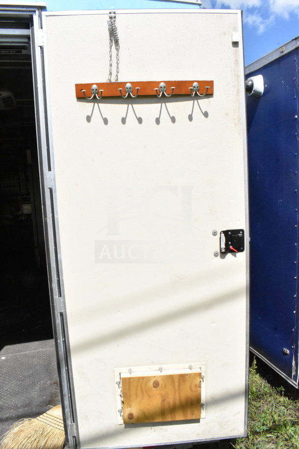 2020 Diamond Cargo food trailer door with metal hooks, chain, and lock. Outside view showing condition.