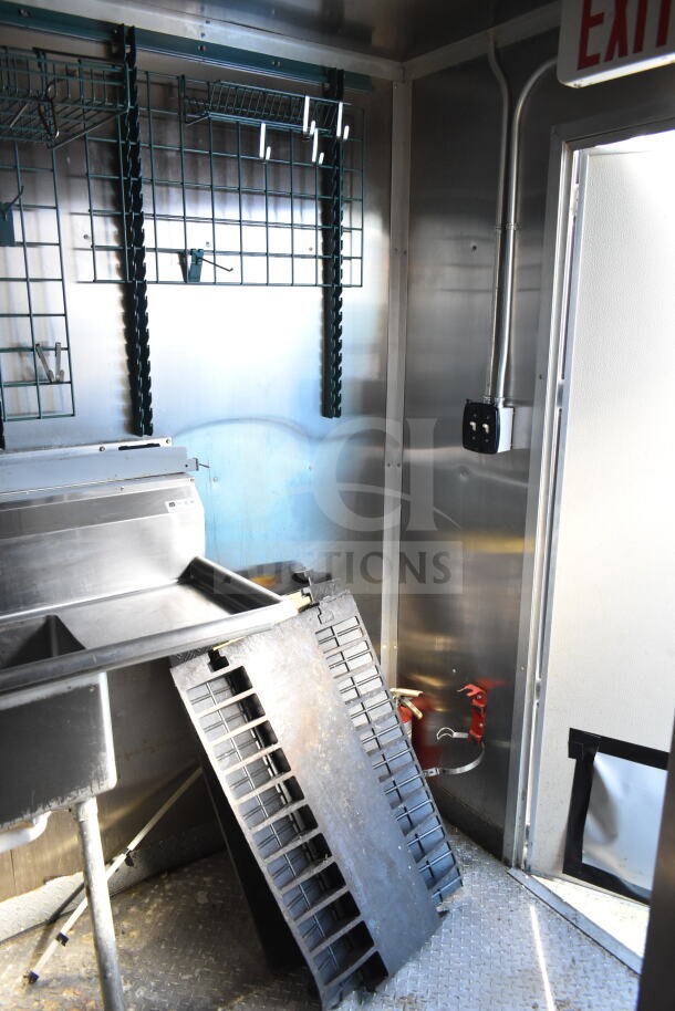 2021 Diamond Cargo 8.5'x24' food trailer interior, stainless steel surfaces, grid racks, visible fire extinguisher, door exit, excellent condition.