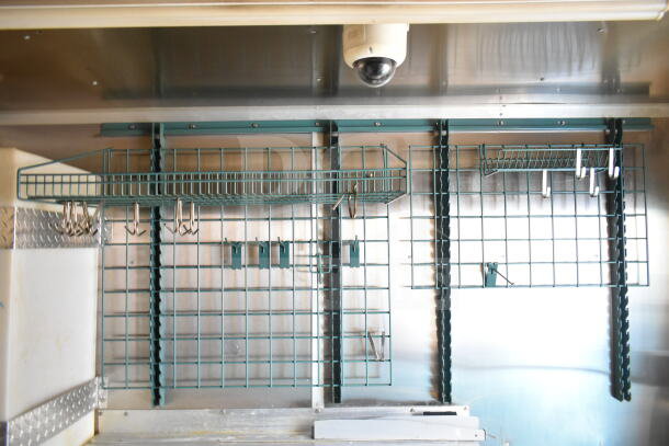 Interior view of a 2021 Diamond Cargo 8.5'x24' food trailer, featuring a mounted storage grid and hanging hooks.