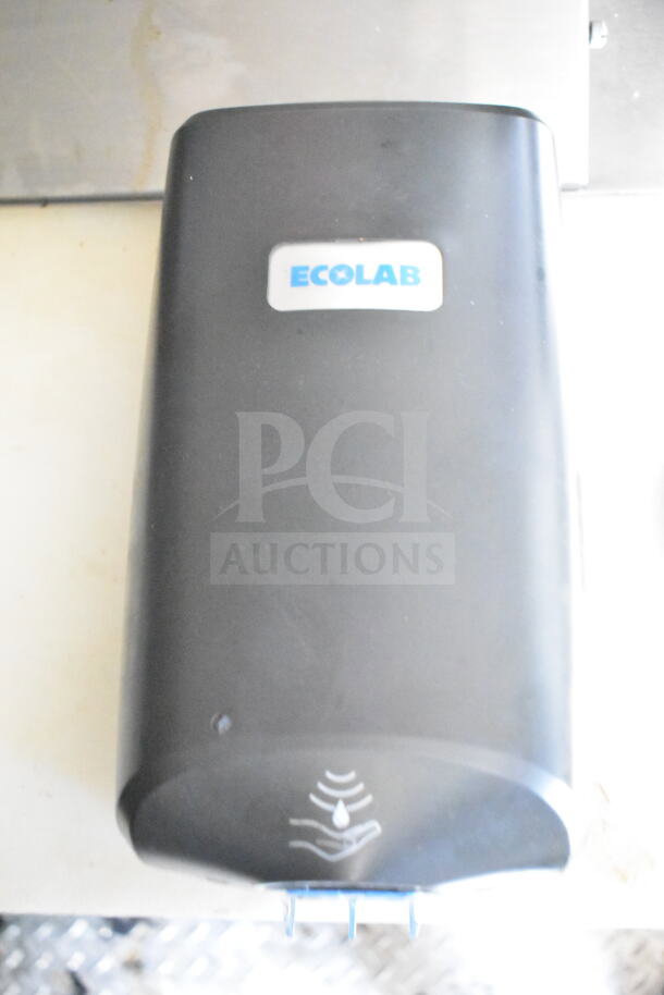 Ecolab soap dispenser with sensor, mounted on wall. Black plastic with white sticker, indicating "ECOLAB."