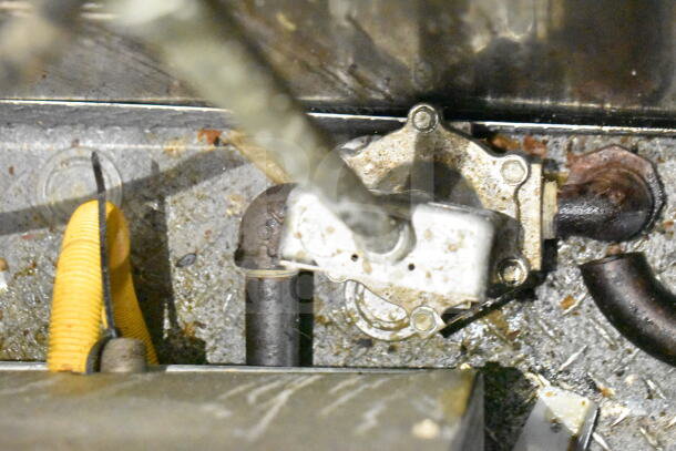 Close-up of a mechanical component in the 2021 Diamond Cargo 8.5'x24' food trailer. The image shows part of the undercarriage with piping and connectors, indicative of used condition likely from kitchen equipment usage.