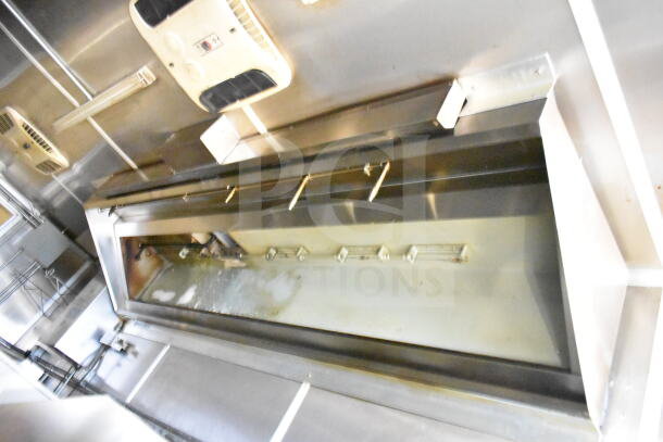 "Interior of 2021 Diamond Cargo 8.5'x24' food trailer showing grease hood and suppression system; stainless steel finish."