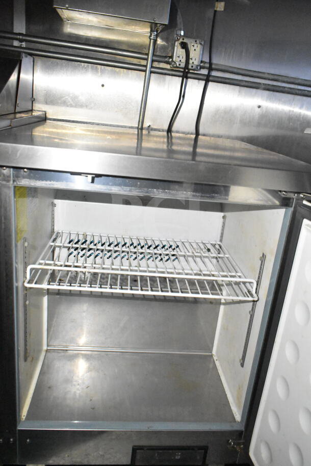 Interior view of 2021 Diamond Cargo food trailer refrigeration unit, featuring a wire shelf and stainless steel interior.