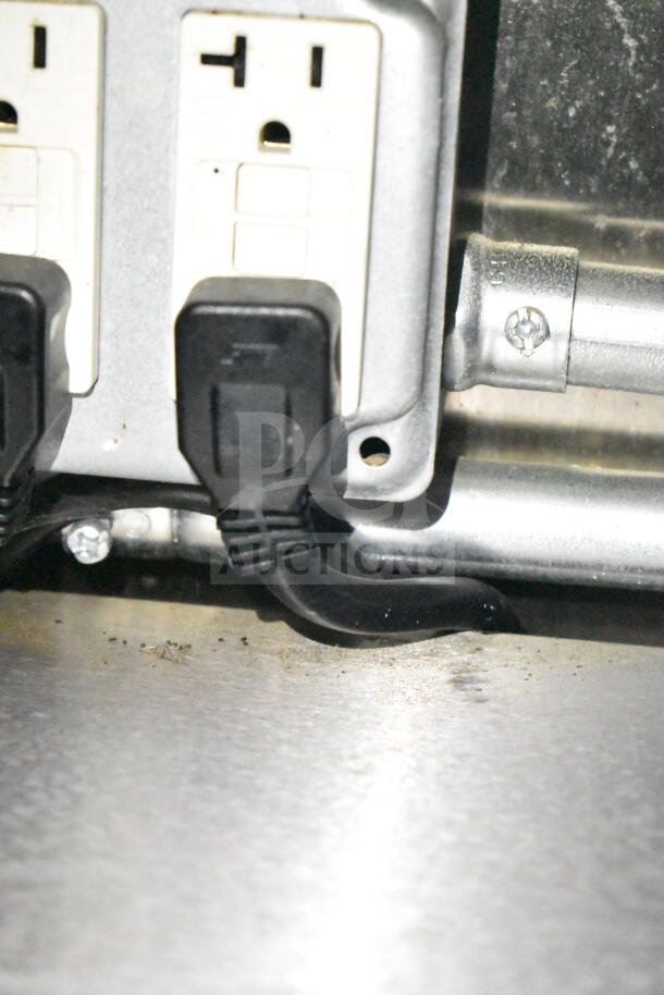 Close-up of electrical outlets with black cords connected in a 2021 Diamond Cargo food trailer, featuring a grease hood and suppression system.