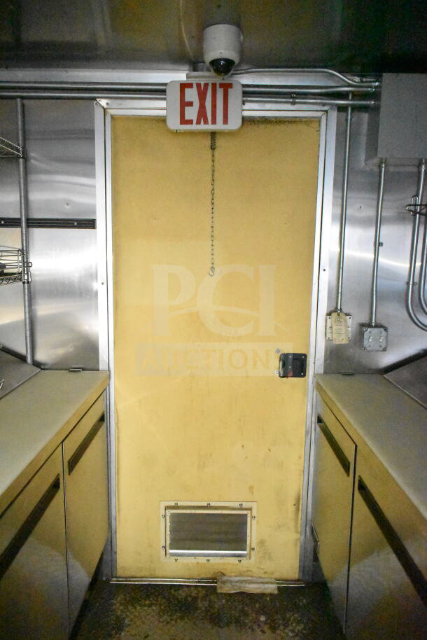 Interior of 2021 Diamond Cargo 8.5'x24' food trailer, featuring stainless steel surfaces. Visible exit sign above door.