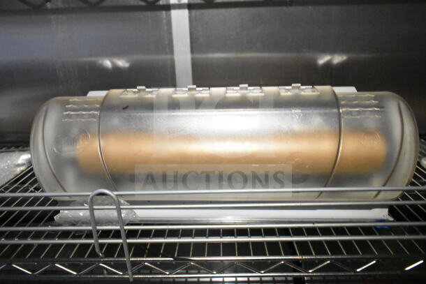 Clear plastic container with a roll inside, on a metal rack in a Diamond Cargo food trailer.