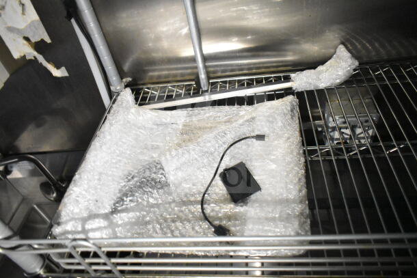 Bubble-wrapped item inside the 2021 Diamond Cargo food trailer with visible wiring and shelving.