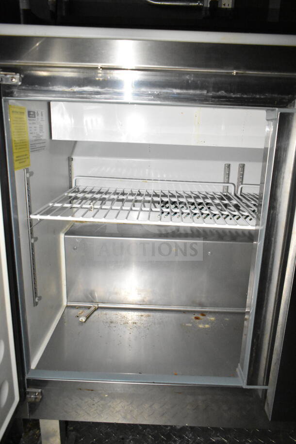 Interior view of a refrigerator in a 2021 Diamond Cargo 8.5'x24' food trailer, showing wire shelves and stainless steel surfaces.
