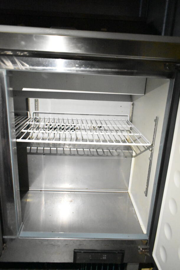 Interior view of refrigeration unit inside 2021 Diamond Cargo 8.5'x24' food trailer, featuring a metal shelf and durable construction.