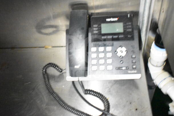Yealink desk phone on a metallic surface, coiled cord visible, part of a 2021 Diamond Cargo 8.5'x24' food trailer.