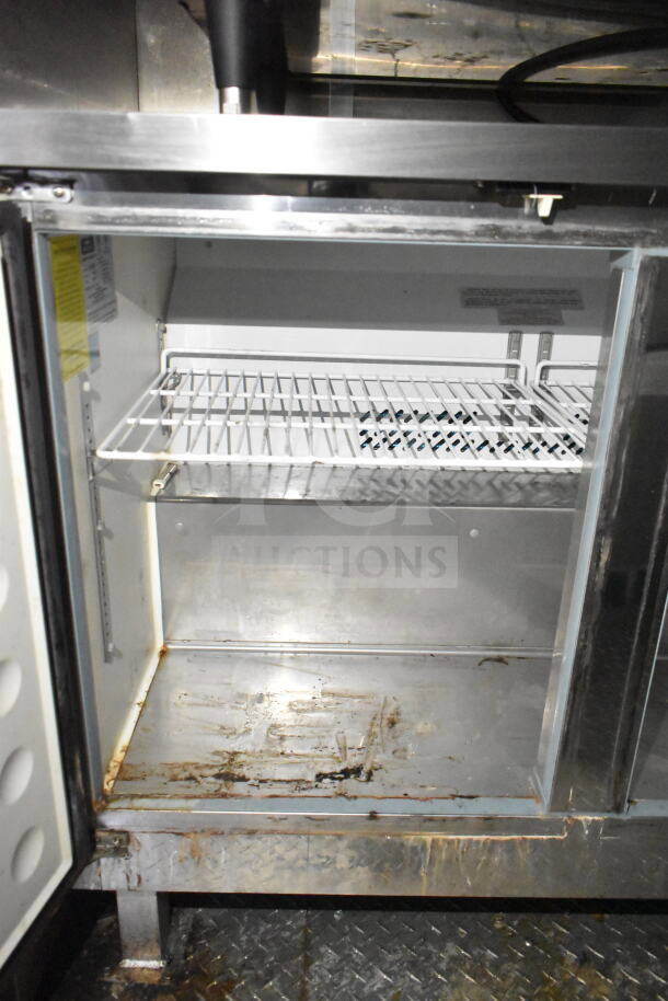 Interior view of Diamond Cargo food trailer's refrigeration unit. Visible wire shelf, moderate wear, and signs of use.