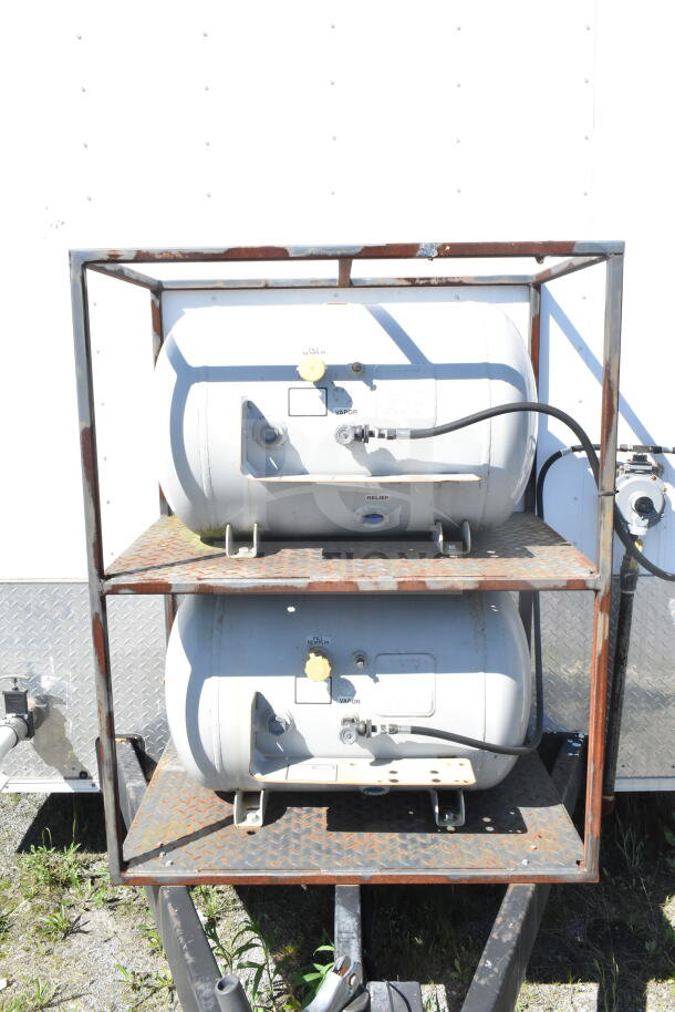 2021 Diamond Cargo 8.5'x24' food trailer propane tanks in rusted metal frame, essential for gas appliances.