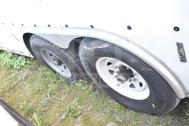 2021 Diamond Cargo 8.5'x24' food trailer wheels, white rims, dual axle, on grass, part of VIN 53NBE242XM1089713 visible.