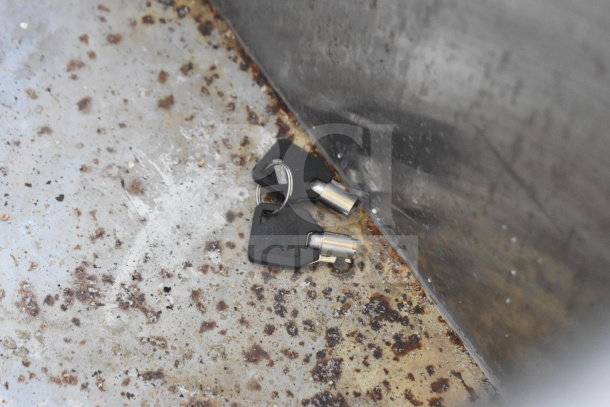 Keys on a metal surface, slightly rusted, part of a 2021 Diamond Cargo 8.5'x24' Food Trailer, VIN: 53NBE2424M1089867.