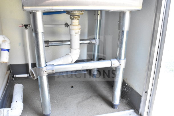 Under-sink plumbing in 2021 Diamond Cargo 8.5'x24' food trailer, showing sturdy metal framework and PVC piping.
