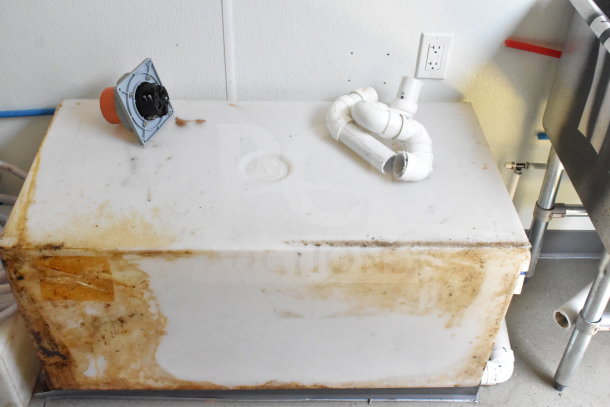 Alt text: Interior of a 2021 Diamond Cargo 8.5'x24' Food Trailer showing a white storage tank with some stains and plumbing components.