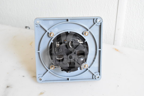 A wall-mounted power outlet socket with a black center and silver screws on a light gray plate.