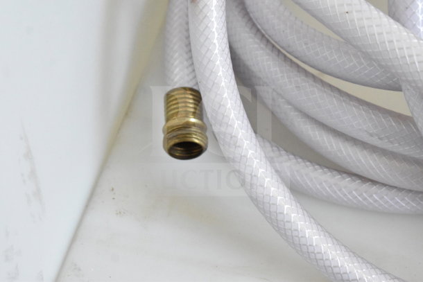 Coiled white reinforced hose with brass fitting in clean condition, located in a food trailer.