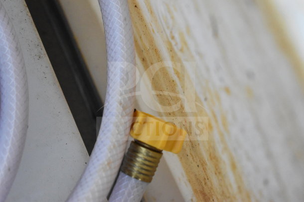 Close-up of a yellow valve connector attached to a textured white hose, set against a stained wall surface.