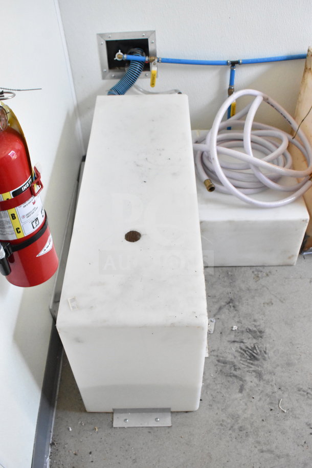 Interior of 2021 Diamond Cargo 8.5'x24' food trailer showing a white rectangular tank, coiled hose, and mounted fire extinguisher.