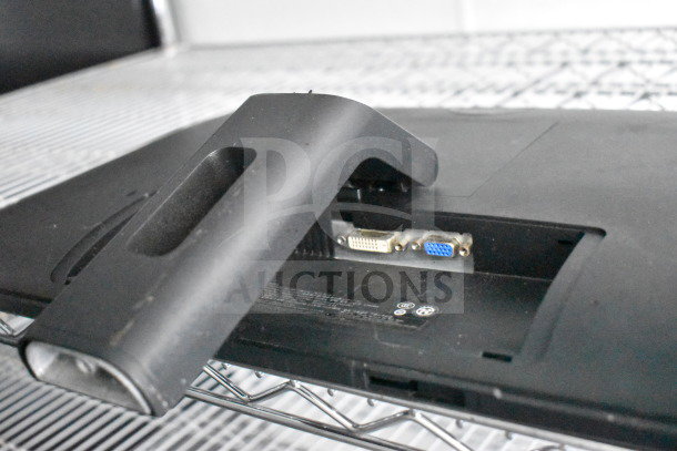 A rear monitor stand bracket with DVI and VGA ports, black, resting on a metal shelf.