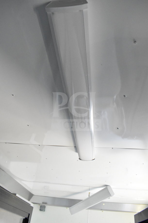 Interior view of a 2021 Diamond Cargo 8.5'x24' cold food/beverage trailer. Features include ceiling lights and insulated white paneling.