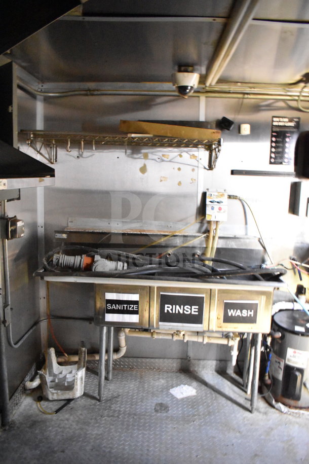 2019 Diamond Cargo 8.5'x24' food trailer interior with grease hood, suppression system, and stainless steel sink labeled sanitize, rinse, wash.