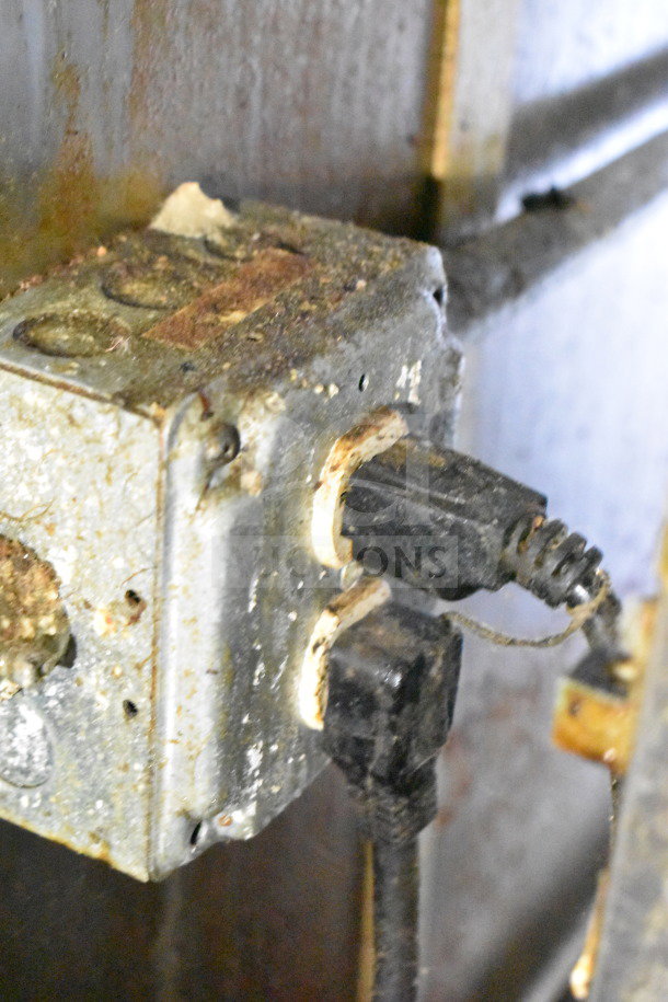 Close-up of an electrical outlet with visible rust and grime, indicating wear and age.