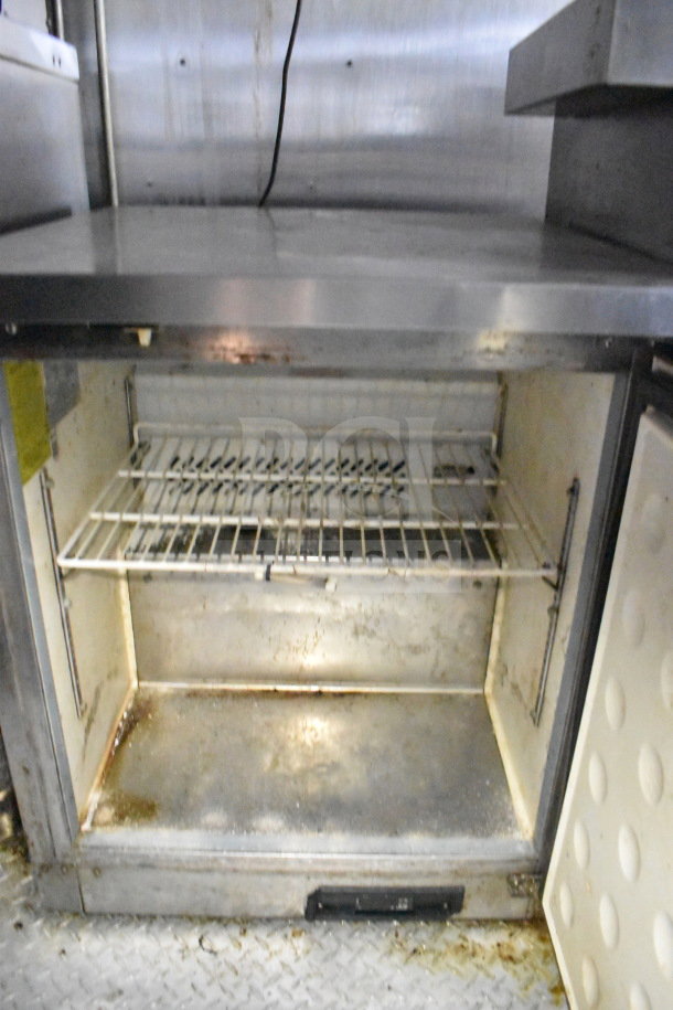 2019 Diamond Cargo 8.5'x24' food trailer interior showing built-in refrigeration unit, wire shelf, and stainless steel surfaces.