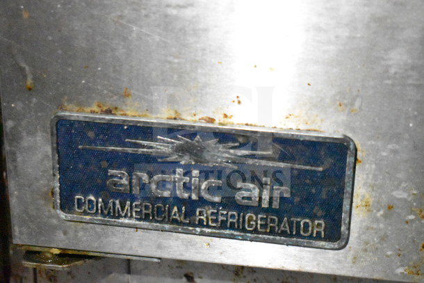 Arctic Air commercial refrigerator label, stainless steel surface showing signs of wear and rust.