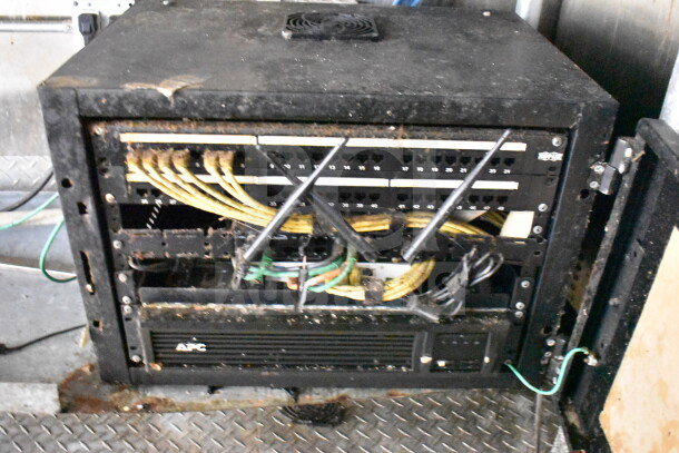 Server rack with cables and APC unit in a Diamond Cargo food trailer, visible wear and rust.