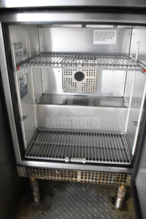 Interior view of a refrigerator in a 2019 Diamond Cargo 8.5'x24' food trailer. Features shelving for storage.