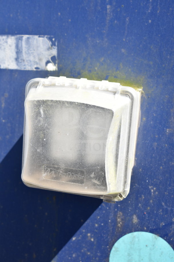Close-up of a TayMac electrical outlet cover on a blue surface of a 2019 Diamond Cargo food trailer.
