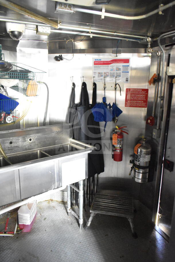 2020 LGS TX 8.5'x24' food trailer interior, featuring a stainless steel sink, fire extinguishers, and cleaning supplies.
