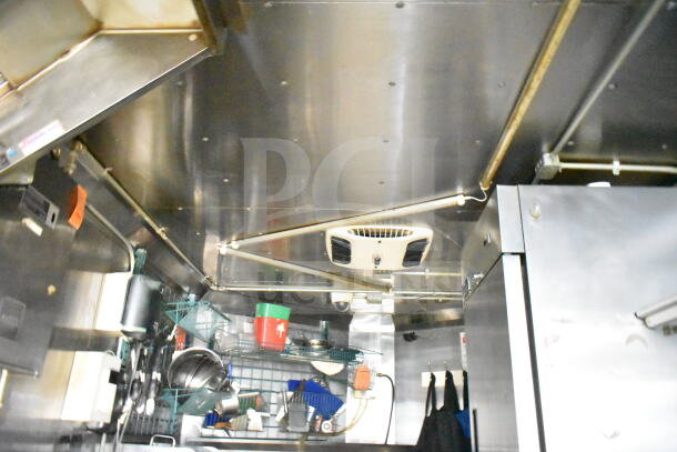 2020 LGS TX 8.5'x24' food trailer interior with CaptiveAire grease hood, shelving, cookware, and refrigeration unit.