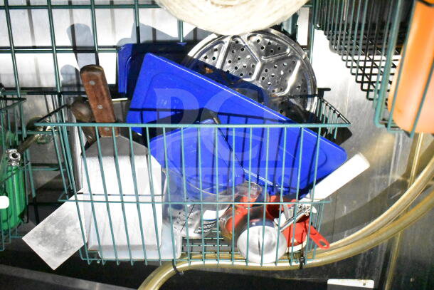 Kitchen utensils and equipment stored in a metal wire rack. Includes spatulas, lids, and measuring cups.