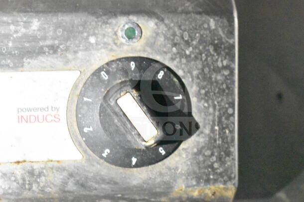 Close-up of a dusty control knob on a food trailer. The label reads "powered by INDUCS."