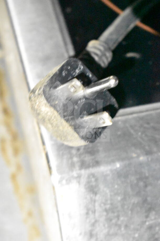 Close-up of the power plug for the 2020 LGS TX food trailer, showing wear and metal prongs on stainless steel surface.