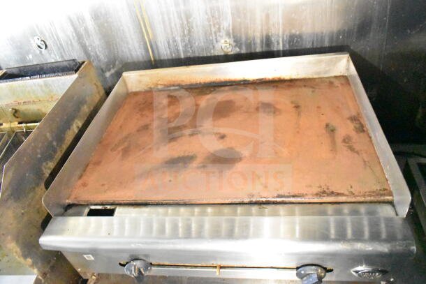 Industrial griddle inside 2020 LGS TX food trailer, showing wear. Features include grease hood and suppression system.