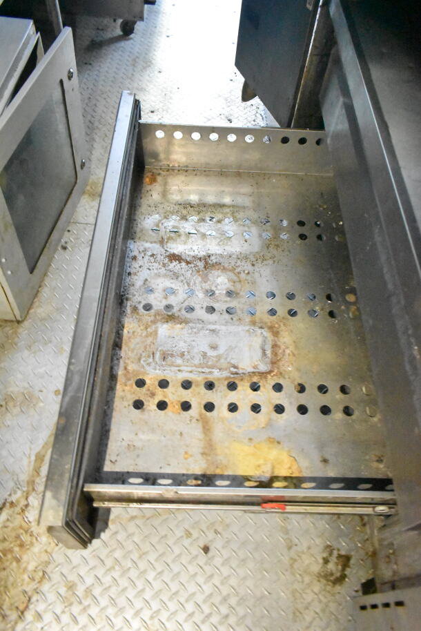 Interior of 2020 LGS TX food trailer showing a pull-out perforated metal drawer, light rust and residue visible, on diamond plate flooring.