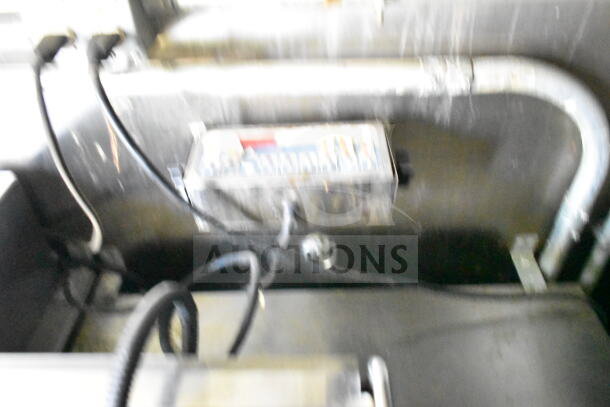 Blurred interior view of 2020 LGS TX food trailer component, featuring wiring and a control unit.
