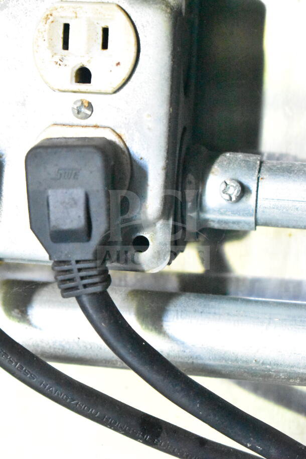 Close-up of a power outlet with a plugged-in cord inside the 2020 LGS TX food trailer.