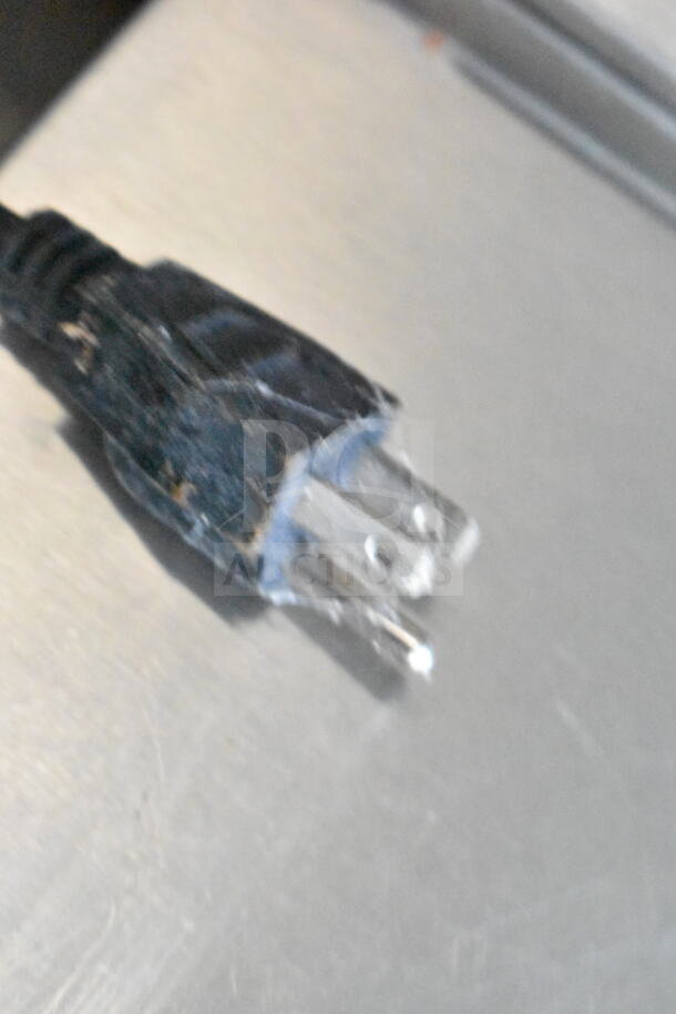 A frayed electrical plug showing signs of wear on a metal surface.
