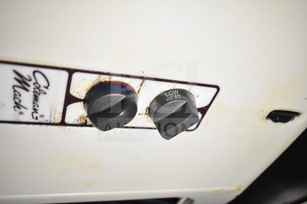 Close-up of Coleman Mack temperature knobs on a lightly stained surface. Controls for low heat visible.
