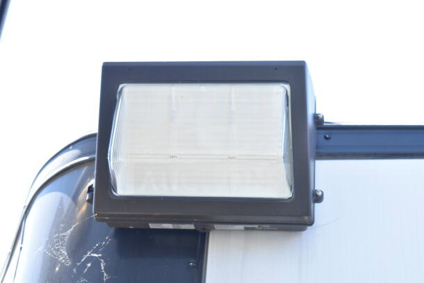 Outdoor light fixture on the 2020 LGS TX 8.5'x24' food trailer. Black frame with clear panel, mounted on trailer exterior.