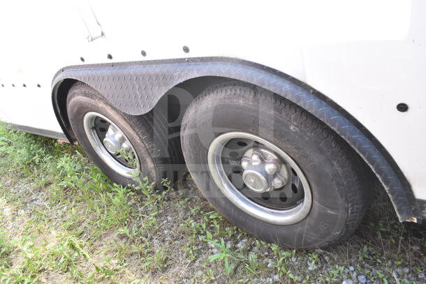 2020 LGS TX 8.5'x24' food trailer tires, dual axle, with diamond plate fender, parked on grass.