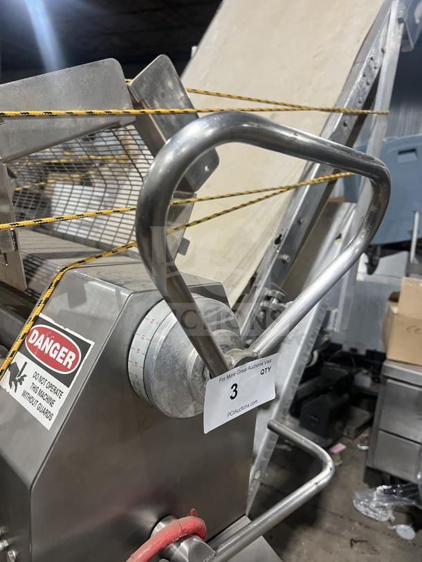 Moline heavy duty reversible conveyorized dough sheeter with foot pedal, stainless steel body, visible safety warnings.